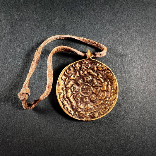 A bronze amulet with Om-Mani-Padme-Hum mantra.