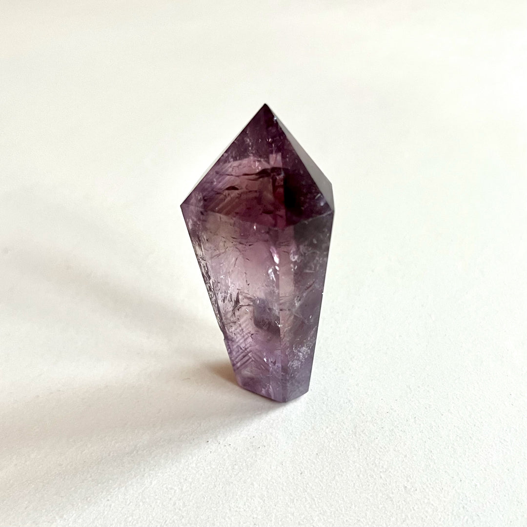 Ametistikärki AA-laatua, kirkkaan violetti kiteinen muoto ja luonnolliset juonteet näkyvissä. - AA-grade amethyst point with vivid purple crystal structure and visible natural striations.