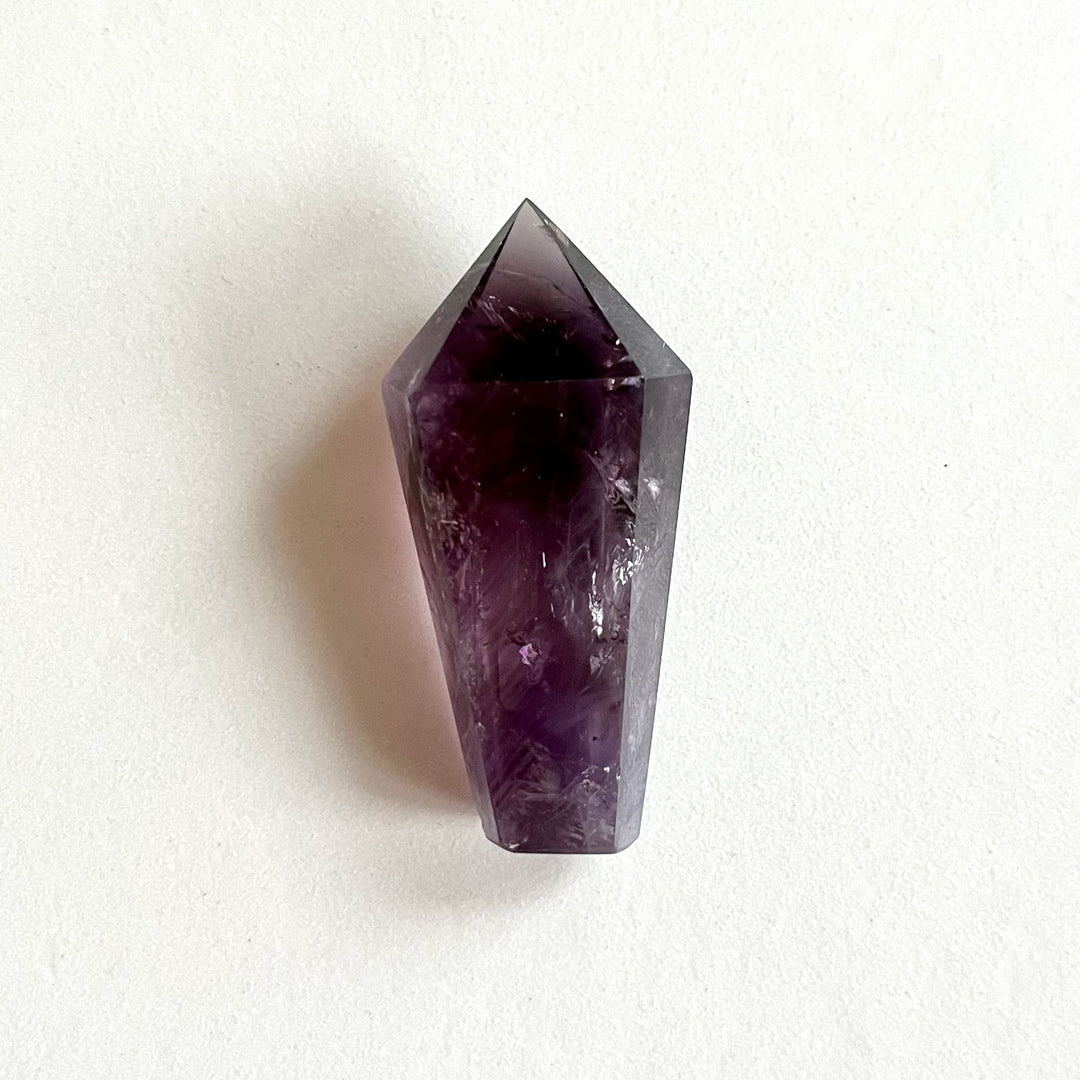 Laadukas AA-luokan ametistikärki, läpikuultava violetti kide jossa kauniita värivaihteluita. - High-quality AA-grade amethyst point, a translucent purple crystal with elegant color variations.