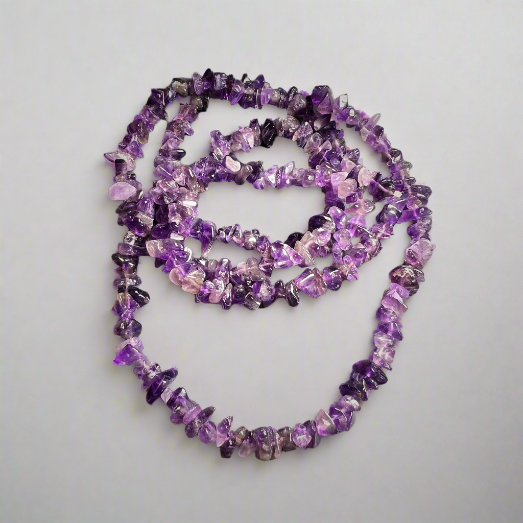 Kuvassa on rullalle käärittu kaulakoru, joka tehty pienistä ametistikivistä. - The image shows a rolled-up necklace made of small amethyst stones.