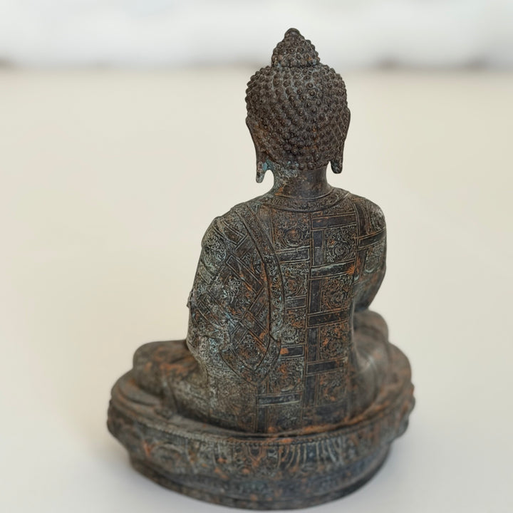 Buddha-patsaan takaosa kokonaisuudessaan; geometrisesti koristeltu viitta ja pyöreä jalusta. - Full rear view of the Buddha statue, displaying the geometrically decorated robe and circular base.