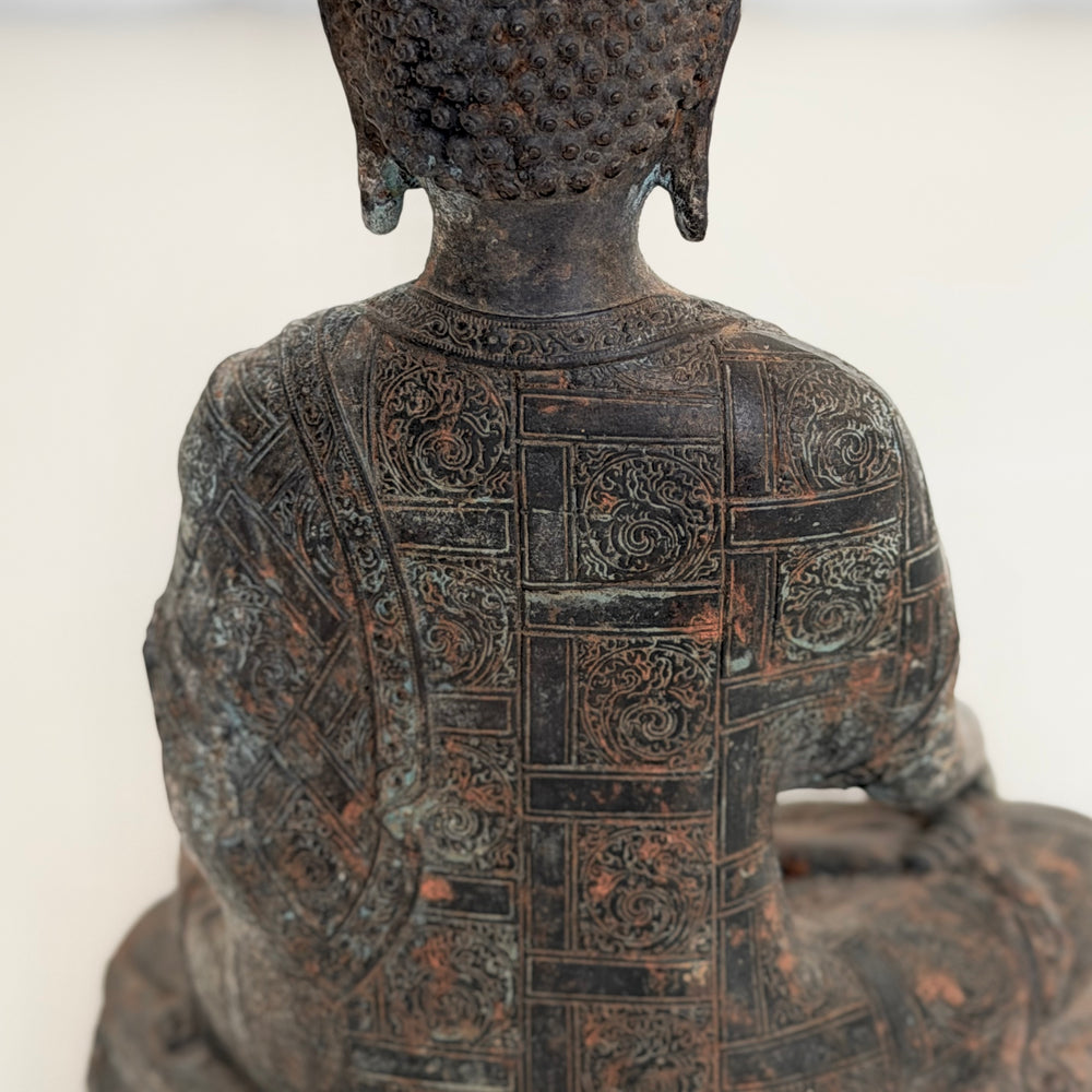 Buddha-patsaan takaosa lähikuvassa; yksityiskohtaisesti koristeltu kaapu ja patinoitu tumma metallipinta. - Close-up of the back of the Buddha statue, showing the intricately decorated robe and dark patinated metal surface.