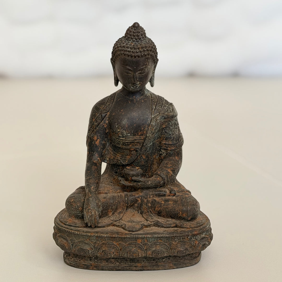 Kokonainen etukuva istuvasta Buddha-patsaasta lootusasennossa jalustalla. - Full frontal view of the seated Buddha statue in lotus position on a decorative base.