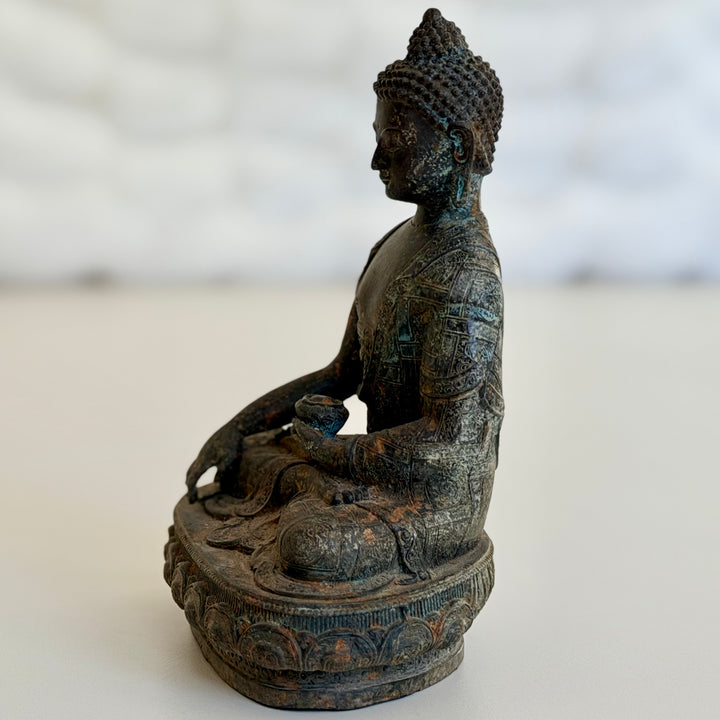 Sivuprofiili istuvasta Buddha-patsaasta; käsien meditaatioasento ja yksityiskohtainen jalusta. - Side profile of the seated Buddha statue, with hands in meditation posture and a detailed base.