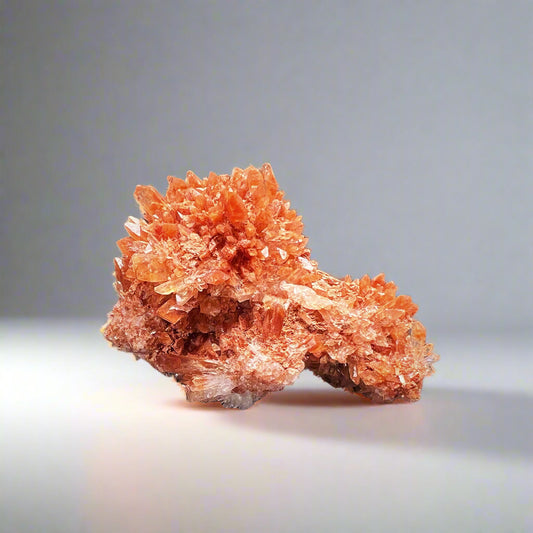 Oranssi creedite-klusteri, jossa neulasmaisia kiteitä. Harvinainen ja läpikuultava mineraali, jonka luonnollinen muodostelma säteilee energiaa. - Orange creedite cluster with needle-like crystals radiating energy. Rare and translucent mineral with vibrant orange hues in a natural formation.