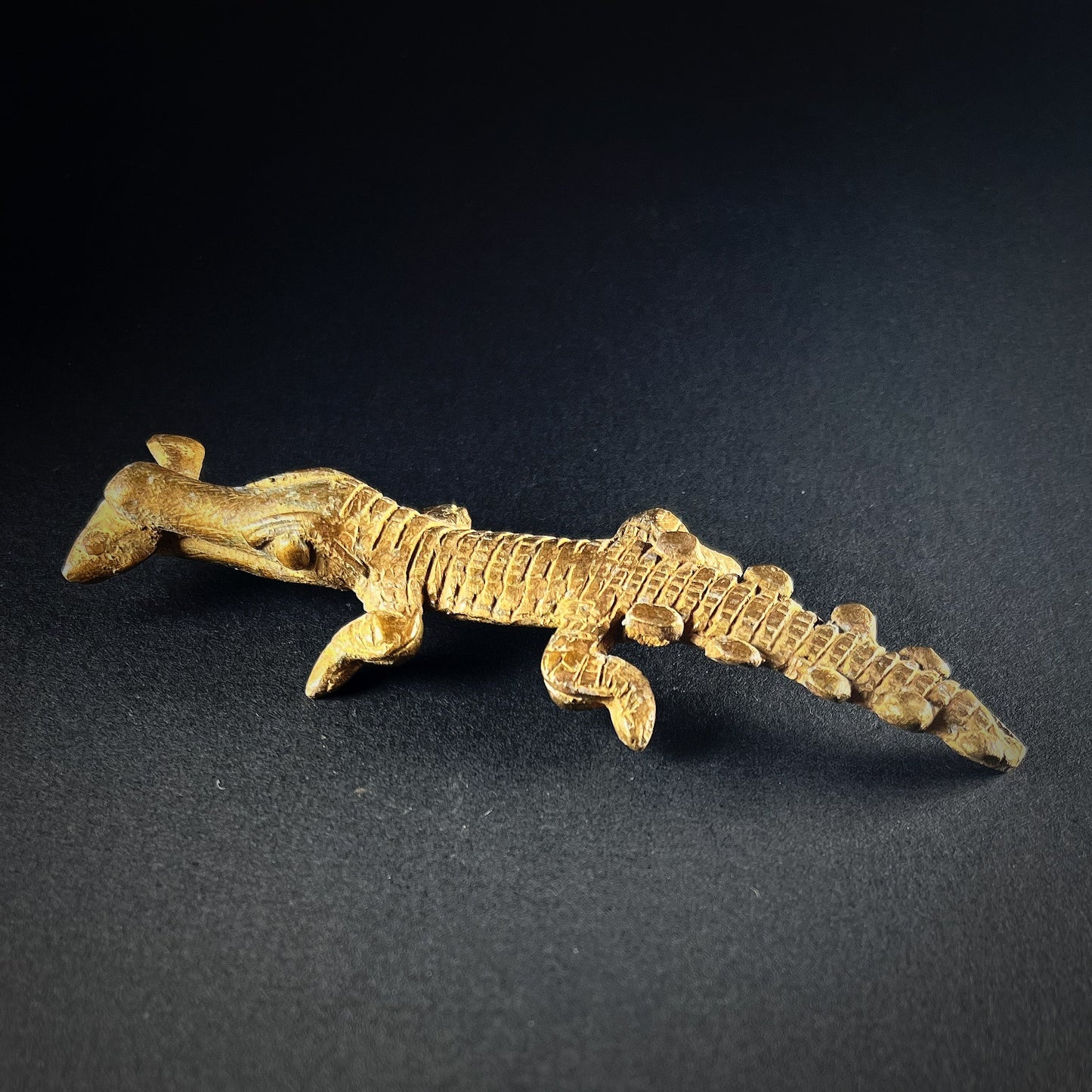 Crocodile amulet made out of bronze. Crocodile has a fish in its mouth. Origin Lobi people in Africa.