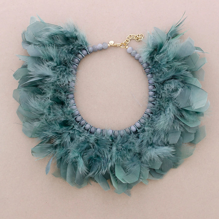 Turkoosi sulkakaulakoru, jossa luonnonsulat on punottu helmillä koristeltuun nauhapohjaan. - Turquoise feather necklace with natural feathers woven into a beaded ribbon base.