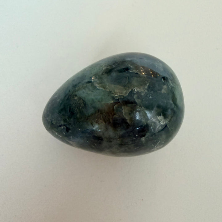 Kiillotettu labradoriittimuna, harmaa perusväri ja sinertävä valonvälke, koko noin 5 cm.
Polished labradorite egg with grey base color and blue light flash, approximately 5 cm in size.