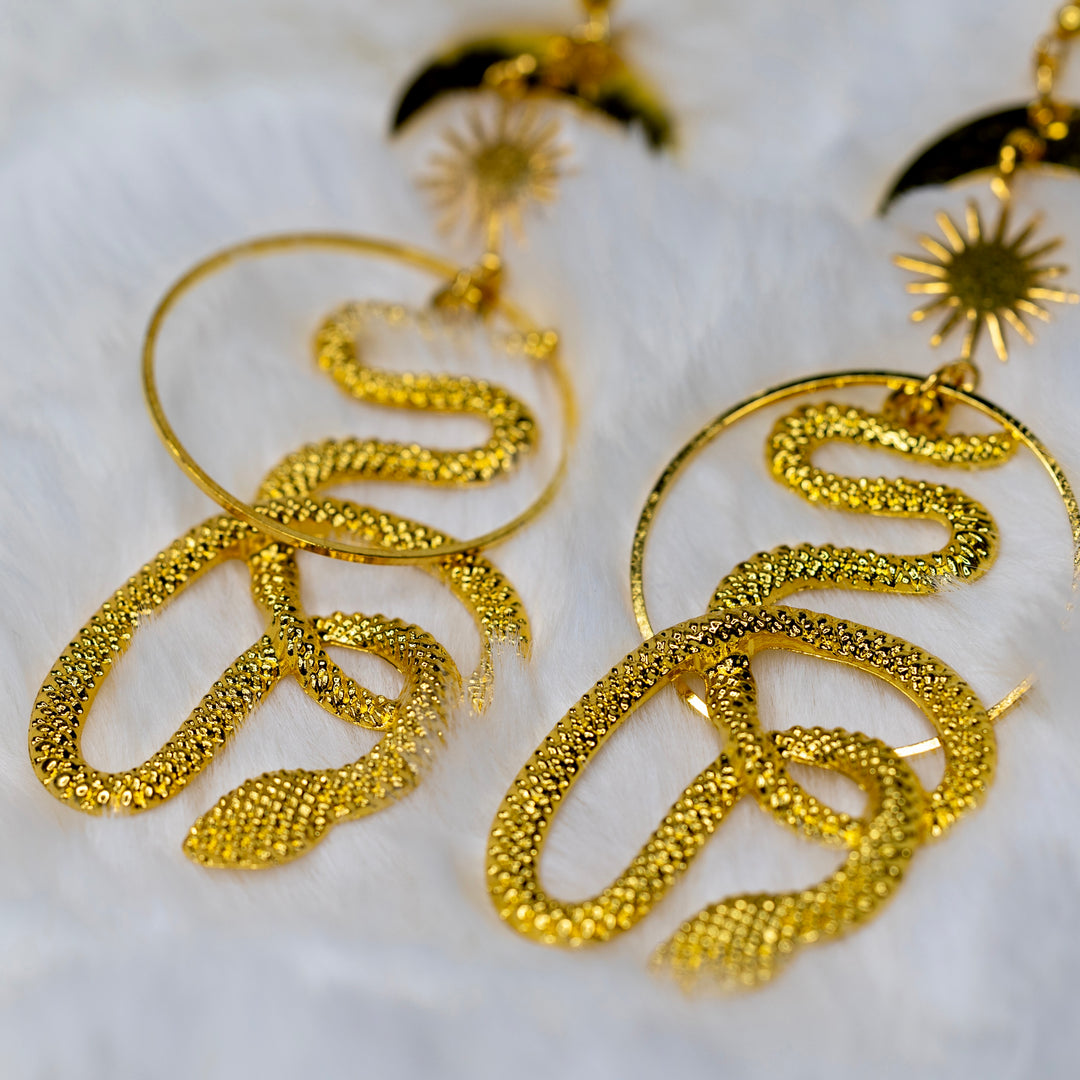 Lähikuva kullanvärisestä käärmeestä korvakorussa, yksityiskohdat esillä. - Close-up of a golden colorer snake on the earring, showcasing details.