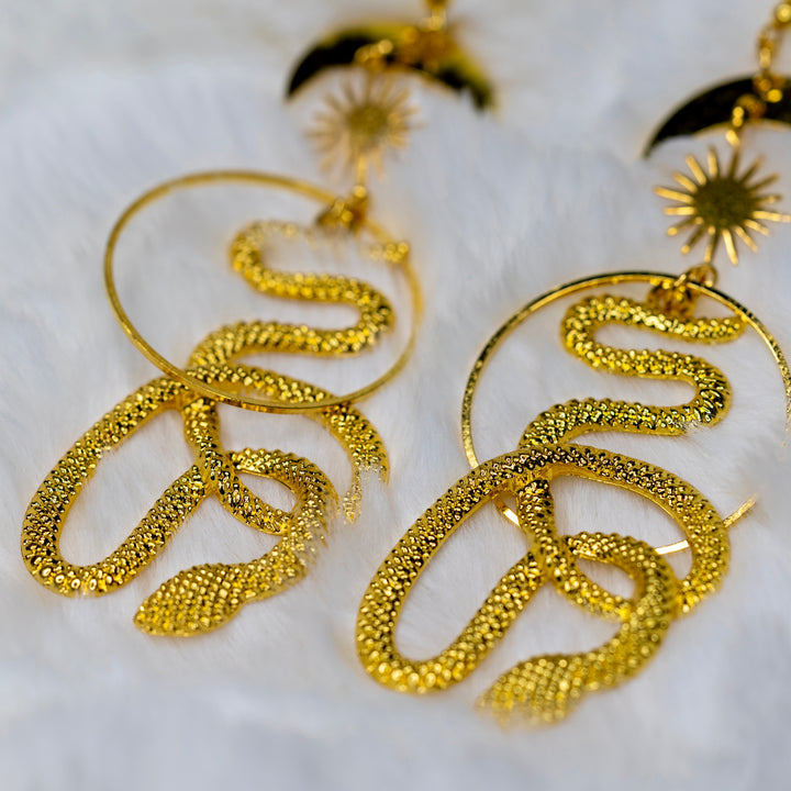 Lähikuva kullanvärisestä käärmeestä korvakorussa, yksityiskohdat esillä. - Close-up of a golden colorer snake on the earring, showcasing details.