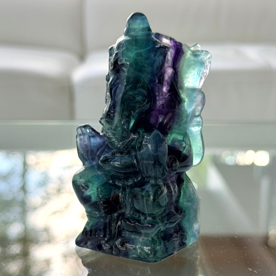 Lähikuva fluoriitti Ganesha -patsaasta, jossa norsupäinen hahmo näkyy sinivihreän ja violetin läpikuultavan kiven sisällä.