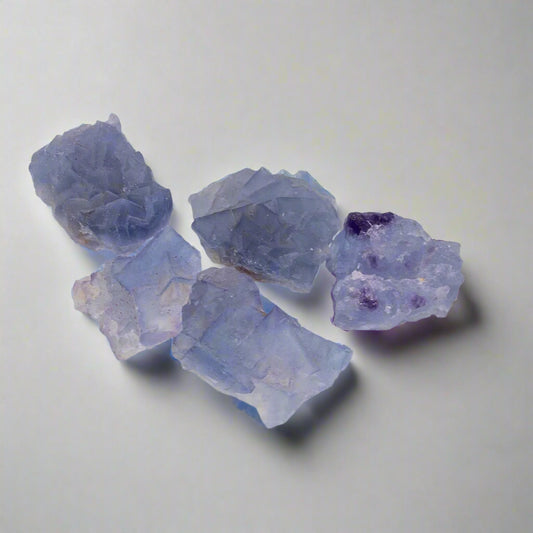 Raakafluoriittipaloja, joissa nähtävissä yhteenkasvaneita kuutiollisia kiteitä. - Raw fluorite pieces with intergrown cubic crystals visible.