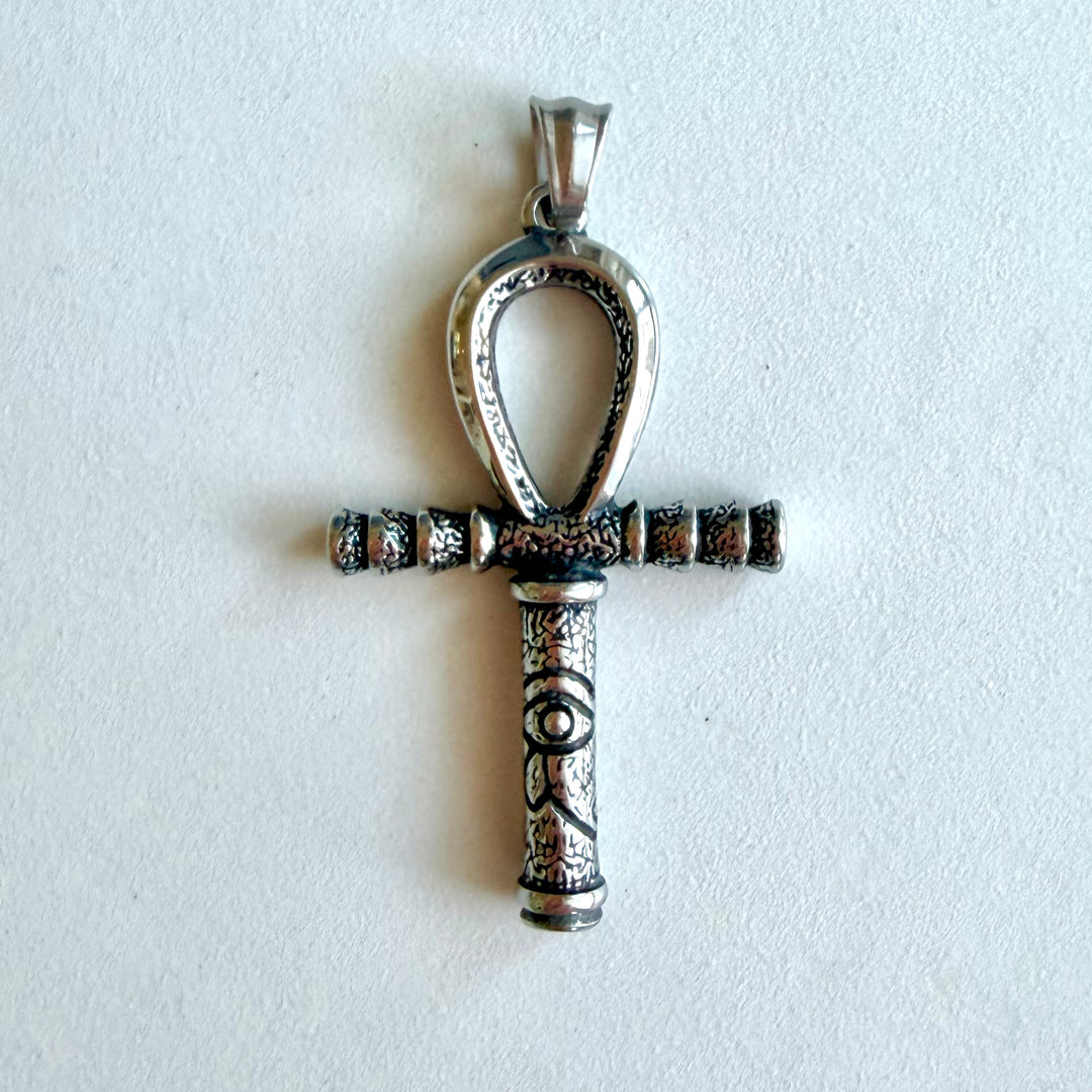 Hopeanvärinen Ankh-amuletti lähikuvassa; kuvioidussa varressa näkyvät mustatut yksityiskohdat ja Horuksen silmä eli Wedjat.
