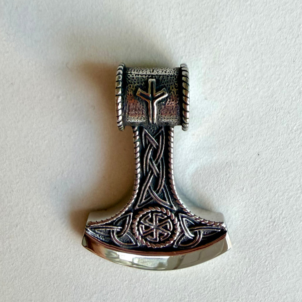 Thorin vasaran muotoinen ruostumattomasta teräksestä valmistettu amuletti lähikuvassa.
