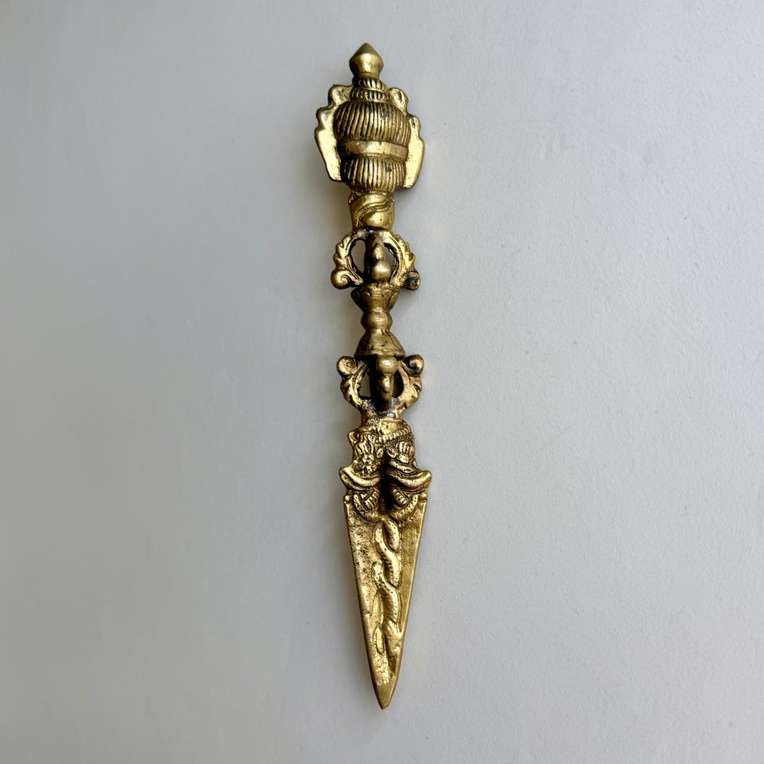 Phurba-rituaalitikari takaa, yläosan uurrettu koristelu, vajra-kahva ja terän käärmeaiheet. / Rear view of the phurba ritual dagger showing the grooved upper decoration, vajra handle and serpent motifs on the blade.
