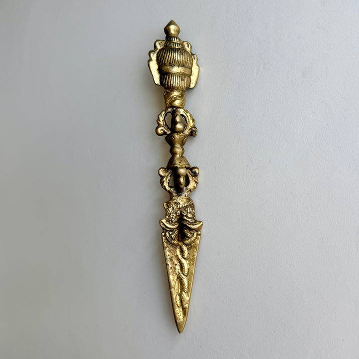 Phurba-rituaalitikari takaa, yläosan uurrettu koristelu, vajra-kahva ja terän käärmeaiheet. / Rear view of the phurba ritual dagger showing the grooved upper decoration, vajra handle and serpent motifs on the blade.