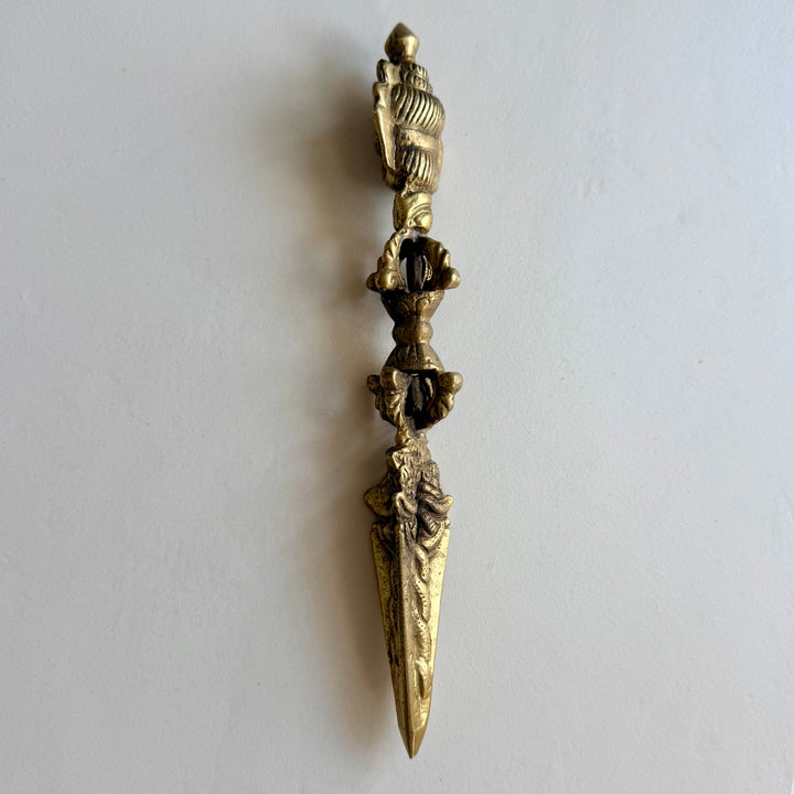 Phurba-rituaalitikari sivulta, kahvan avoimet vajra-aiheet ja kolmiteräisen terän rakenne. / Side view of the phurba ritual dagger showing the open vajra motifs and three-sided blade.