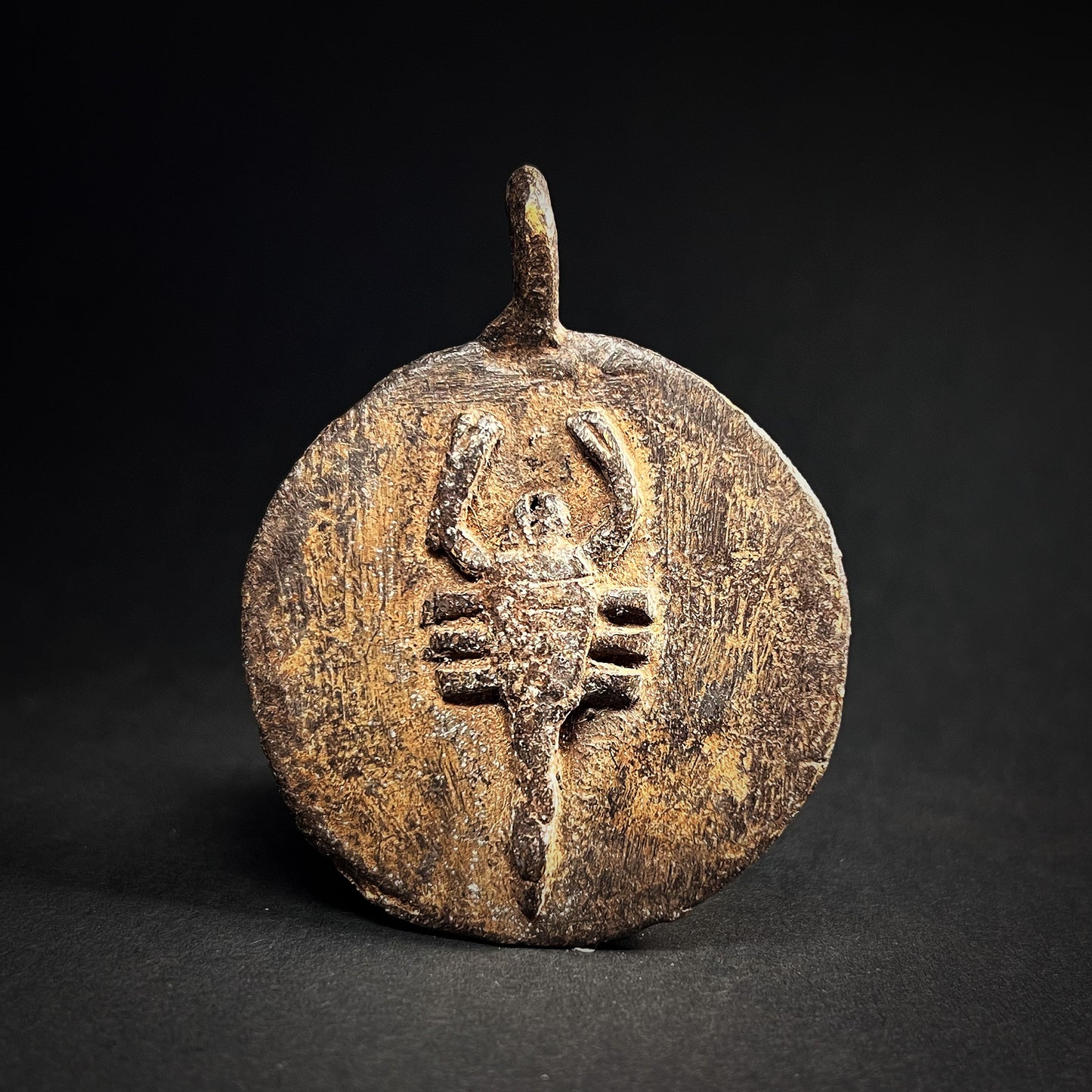 Scorpion amulet from Lori people made of bronze. A round amulet with scorpion image in center.