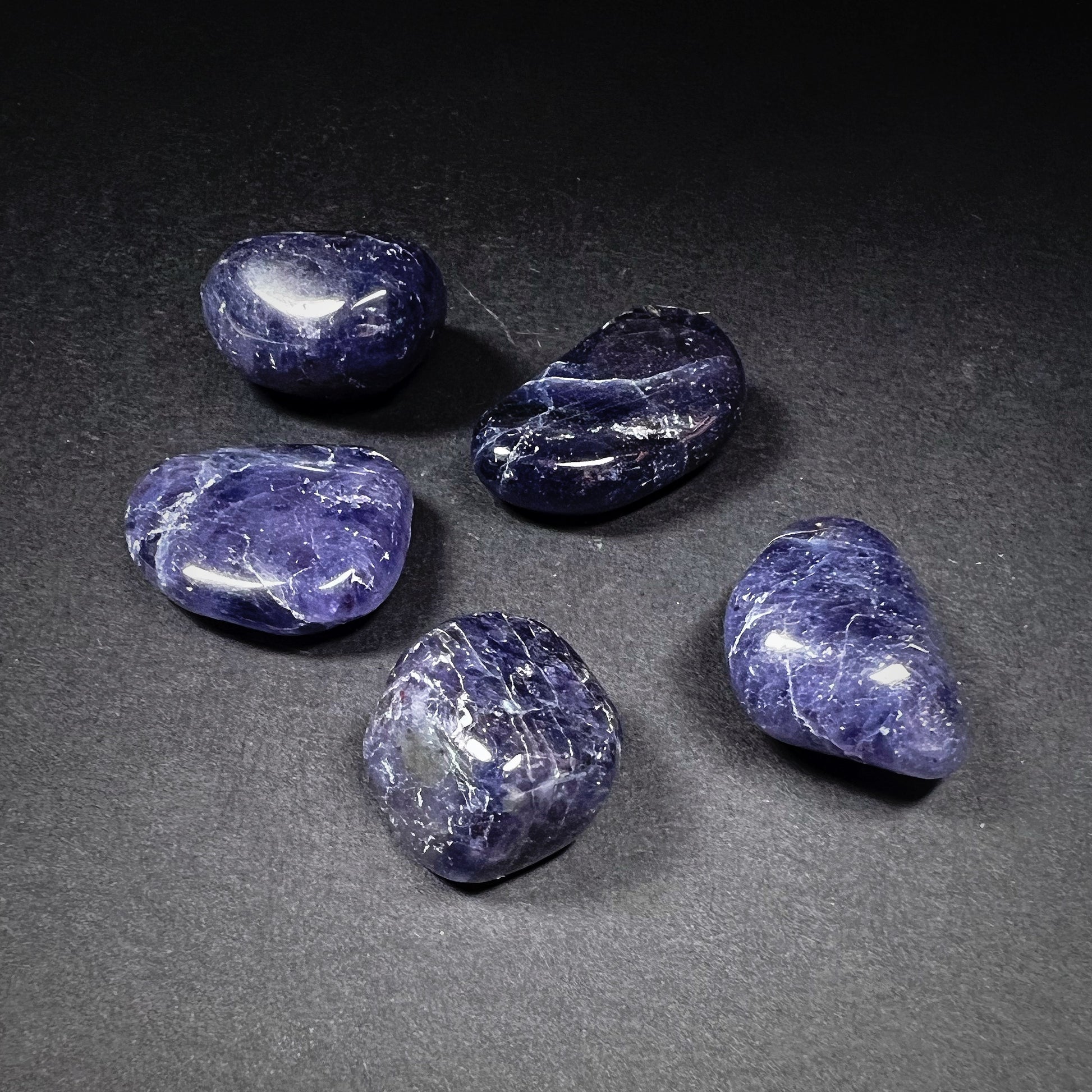 Tumbled iolite stones. Colored blue and violet with white stripes.