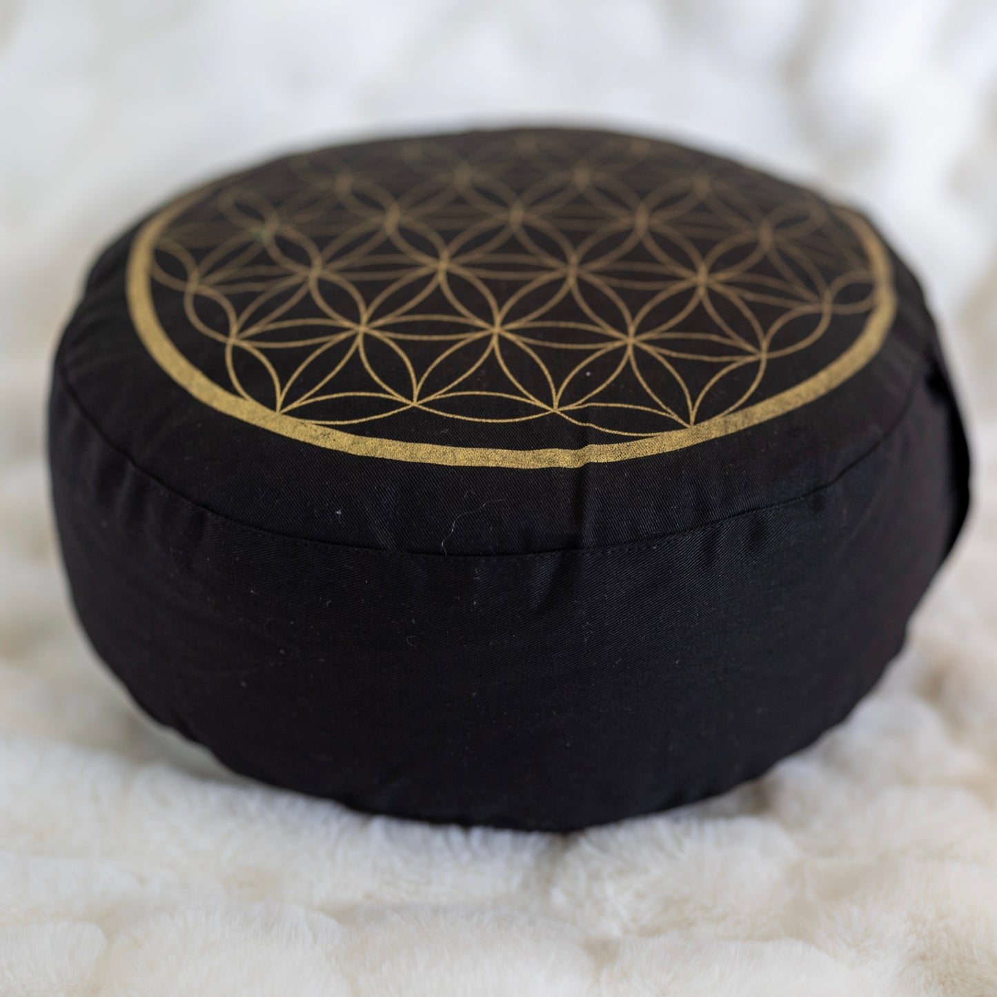 Meditaatiotyyny Flower of Life, musta/kulta, sivulta kuvattuna, joka korostaa sen korkeutta ja tattarinkuoritäytettä - Meditation cushion Flower of Life, black/gold, side view highlighting its height and buckwheat hull filling.