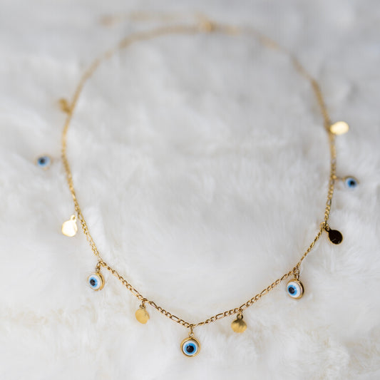 Kokonaan näkyvä kullattu Nazar-kaulakoru, jossa sinisiä silmäamuletteja ja tyylikäs, kullattu ruostumaton teräsketju - A fully visible gold-plated Nazar necklace with a blue eye amulets and a polished stainless steel gilded chain.