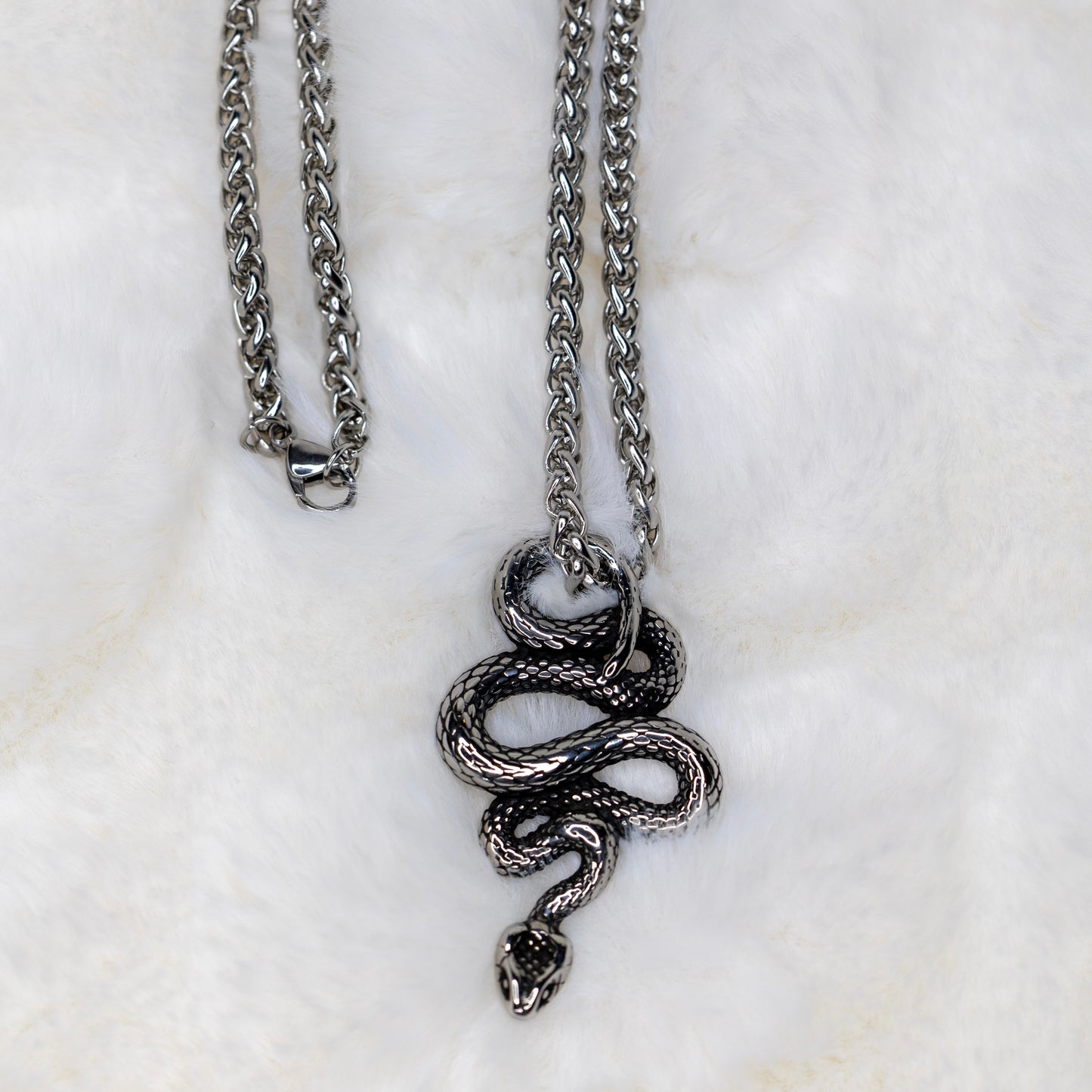 Osittainen näkymä käärmekaulakorusta, keskittyen ketjuun ja amuletin yksityiskohtiin. - Partial view of the snake necklace, focusing on the chain and pendant details.