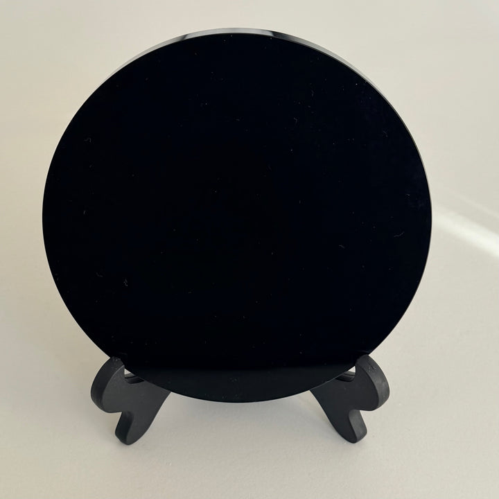 Obsidiaanipeili etupuolelta, syvänmusta kiillotettu pinta jalustalla - Obsidian mirror front view, deep black polished reflective surface on stand