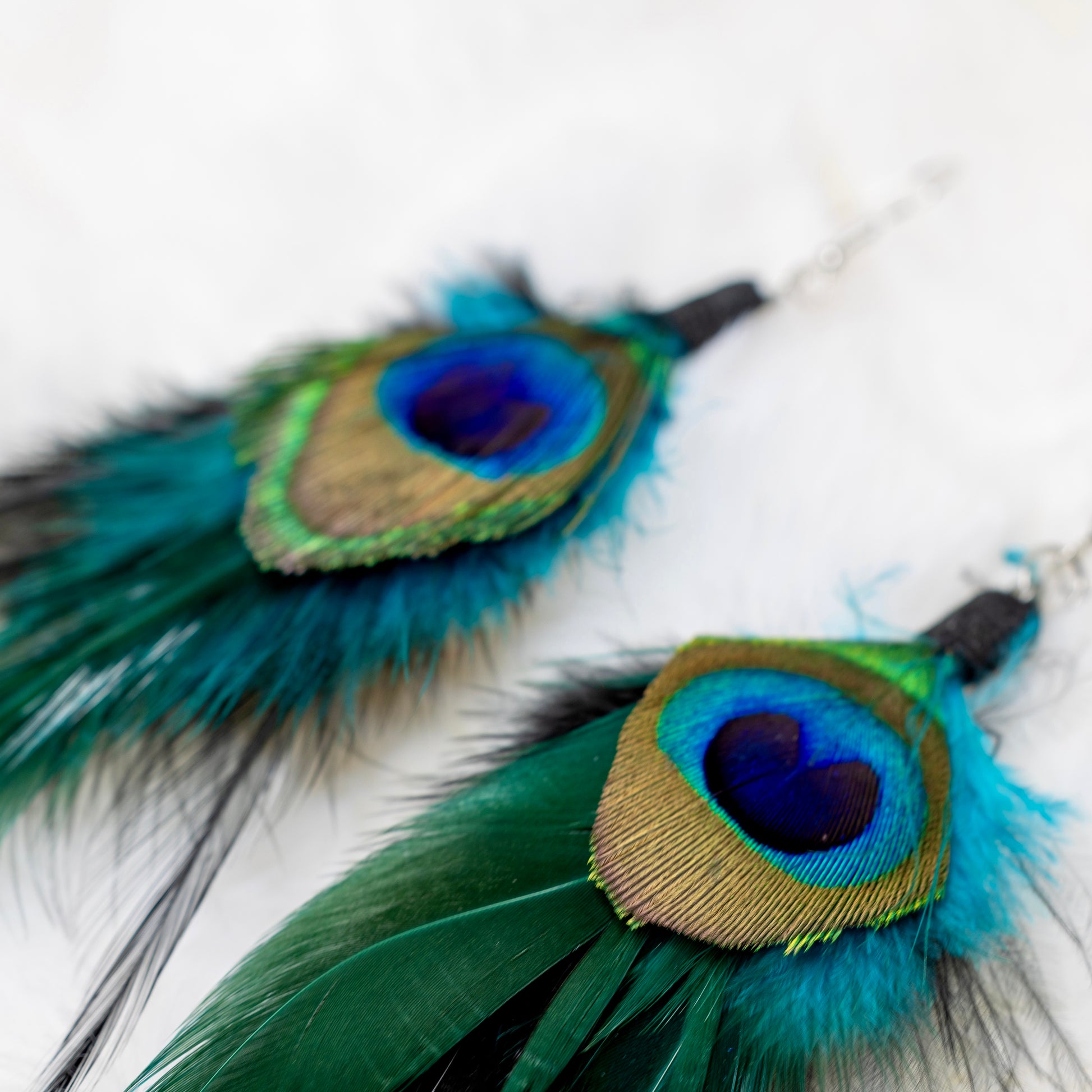 Lähikuva riikinkukon sulan silmästä, jossa näkyvät sen upeat sinisen ja vihreän sävyt. -  Close-up of the peacock feather's eye, showcasing its stunning blue and green hues.