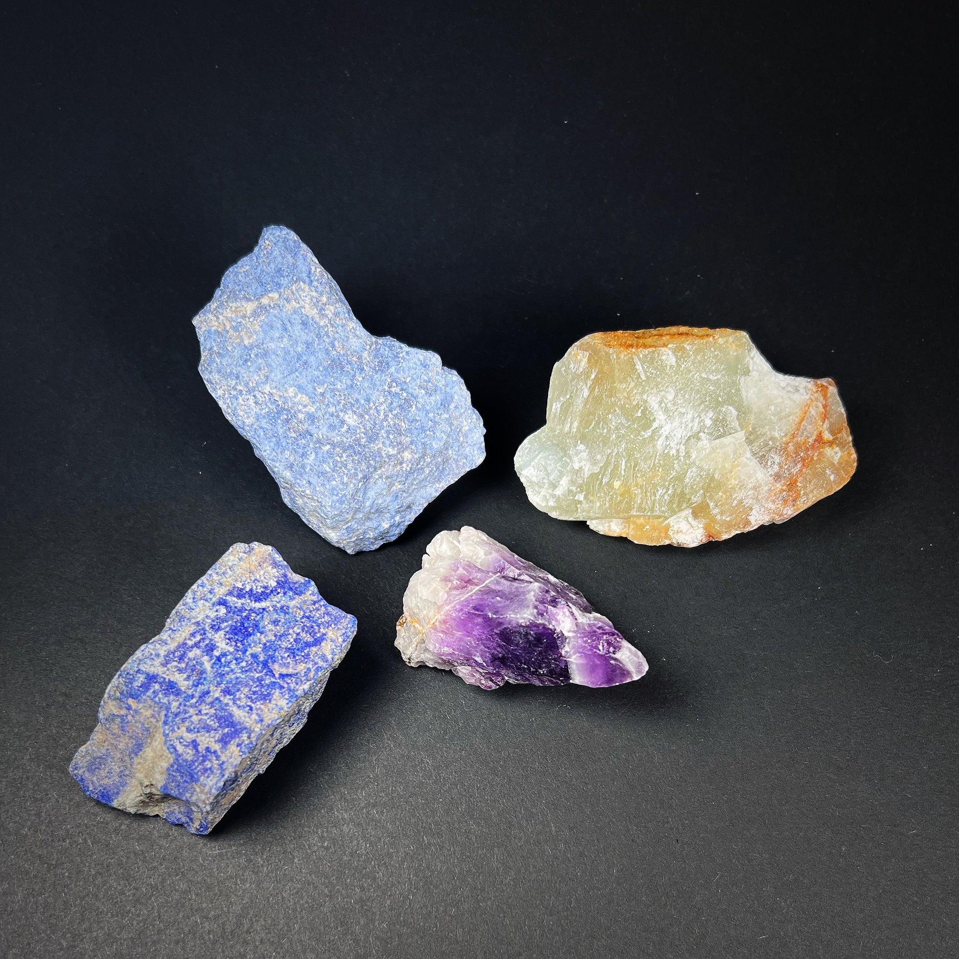 Crystal grid of four raw stones: lapis lazuli, dumortierite, chevron amethyst and blue onyx.