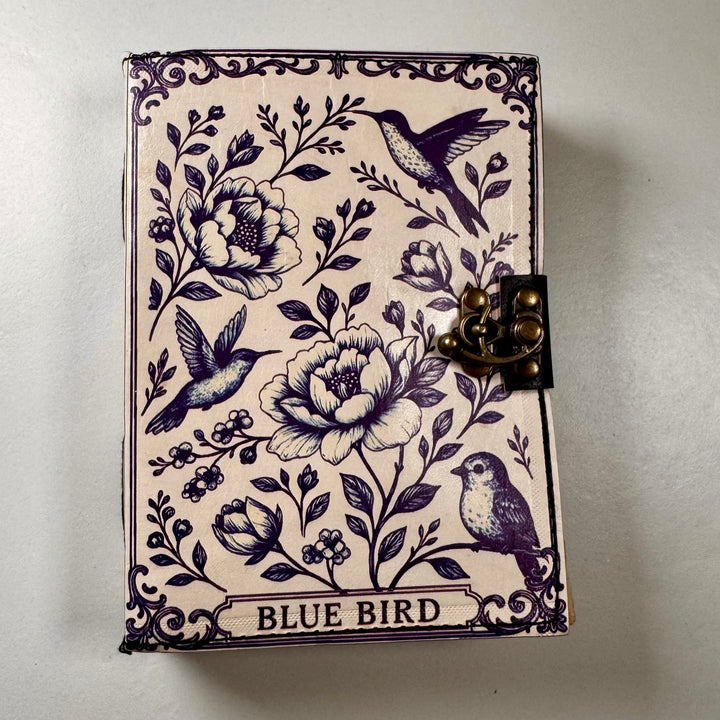 The Blue Bird -muistikirjan etukansi, jossa lintusymboli ja koristeellinen kohokuviointi. - Front cover of The Blue Bird notebook featuring a bird symbol and embossed decorative details.