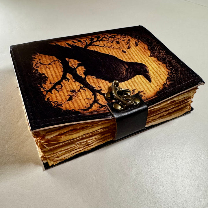 Korppiaiheinen nahkakantinen muistikirja sivusta kuvattuna, esillä kirjan paksuus ja sivut. - Raven-themed leather-bound journal photographed from the side, showing the book’s thickness and pages.