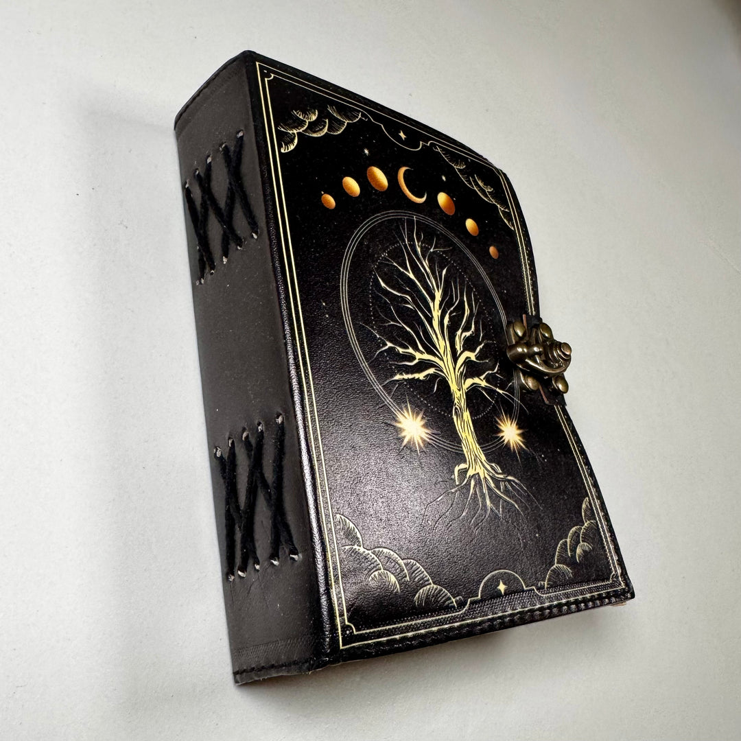 Nahkakantinen The Tree of Life -muistikirja kuvattuna viistosti, esillä käsityön yksityiskohdat. - The Tree of Life leather notebook captured from an angle, highlighting fine craftsmanship details.