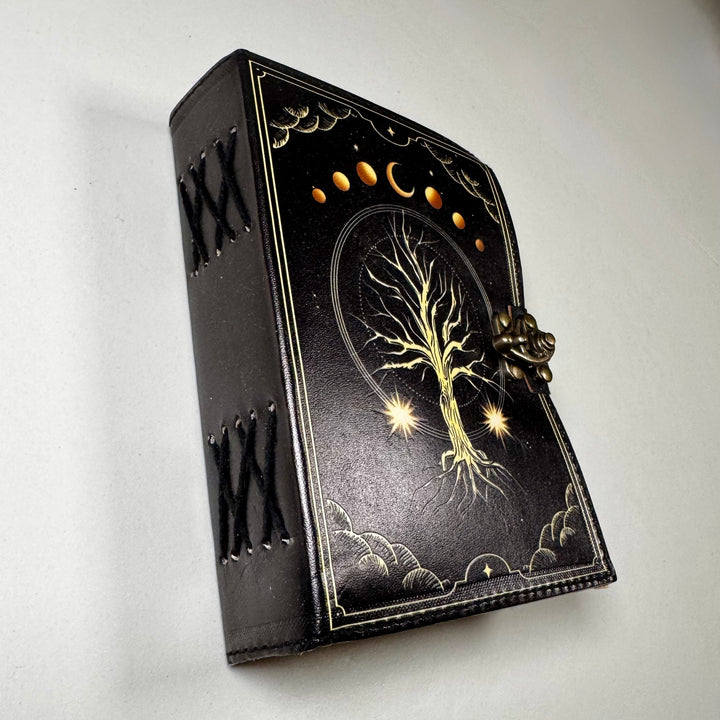 Nahkakantinen The Tree of Life -muistikirja kuvattuna viistosti, esillä käsityön yksityiskohdat. - The Tree of Life leather notebook captured from an angle, highlighting fine craftsmanship details.