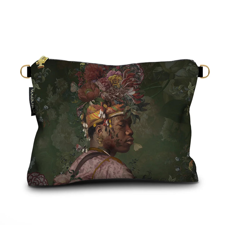 Kuvassa Voglio Bene samettilaukun etupuoli Akeem -kuvituksella, jossa tatuoitu mies kukka-asetelmapäähineessä on kuvattuna vihreällä taustalla.
In the image, the front side of a Voglio Bene velvet bag with the Akeem illustration, depicting a tattooed man wearing a floral headpiece against a green background.