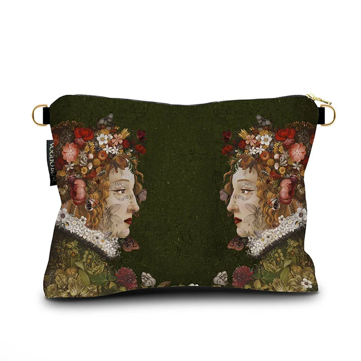 Kuvassa Voglio Bene -samettilaukun takapuoli Flora -kuvituksella. Kaksi tatuoitua punahiuksista naista kukkia hiuksissaan katsovat toisiaan vihreällä taustalla.
The back of the Voglio Bene velvet bag with Flora illustration. Two tattooed red-haired women with flowers in their hair face each other against a green background.