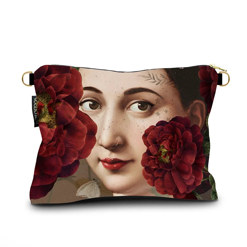 Kuvassa Voglio Bene -samettilaukun takapuoli Fornarina -kuvituksella. Lähikuva tatuoidun naisen kasvoista kukkien reunustamana.
The back of the Voglio Bene velvet bag with Fornarina illustration. Close-up of the tattooed woman’s face framed by flowers.