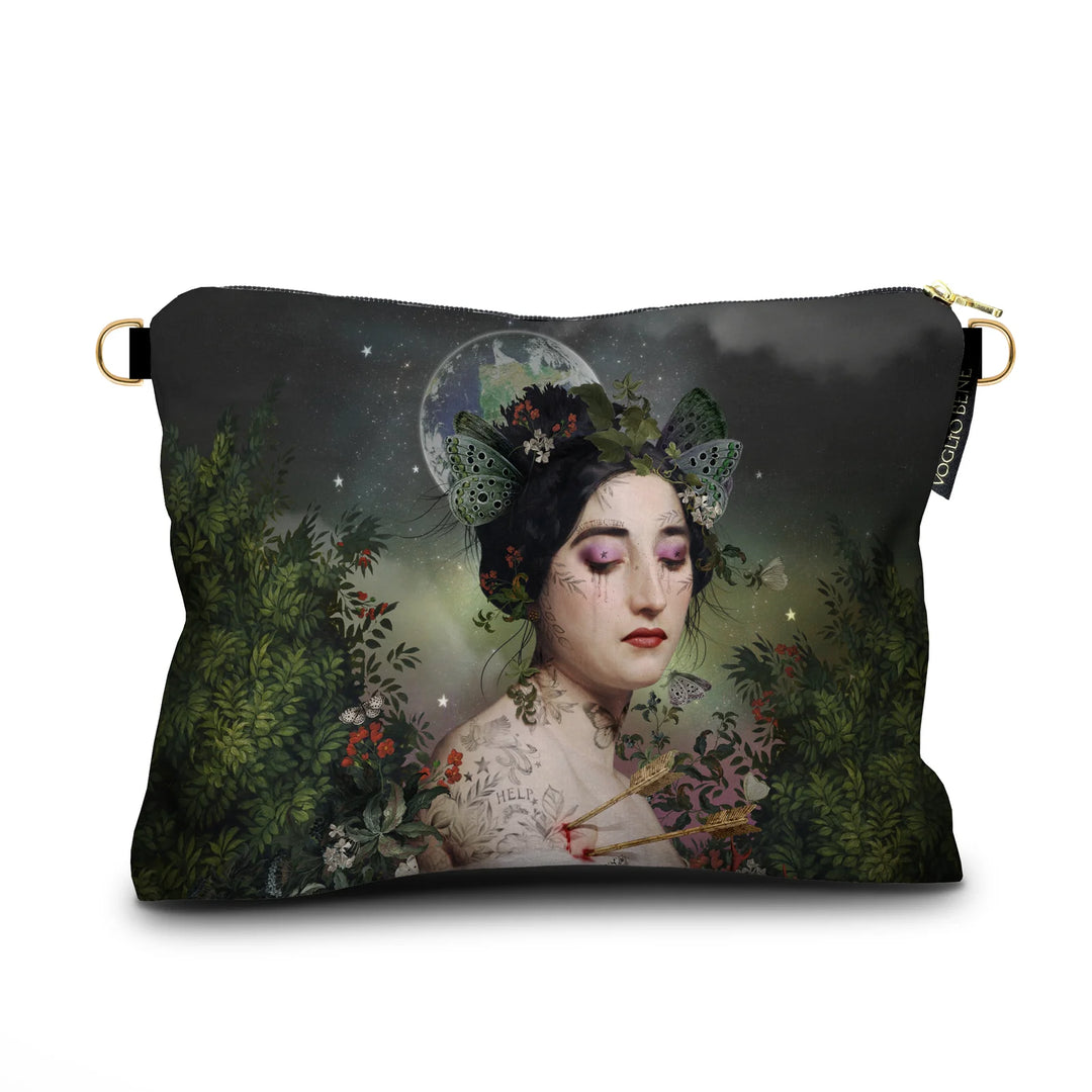 Kuvassa Voglio Bene samettilaukun etupuoli Gaia -kuvituksella, jossa tatuoitu nainen perhosia hiuksissaan katsoo alaspäin, taustalla näkyy avaruus ja maapallo ja reunoilla kasveja.
In the image, the front side of a Voglio Bene velvet bag with the Gaia illustration, depicting a tattooed woman with butterflies in her hair looking downward, with space and Earth in the background and plants along the edges.