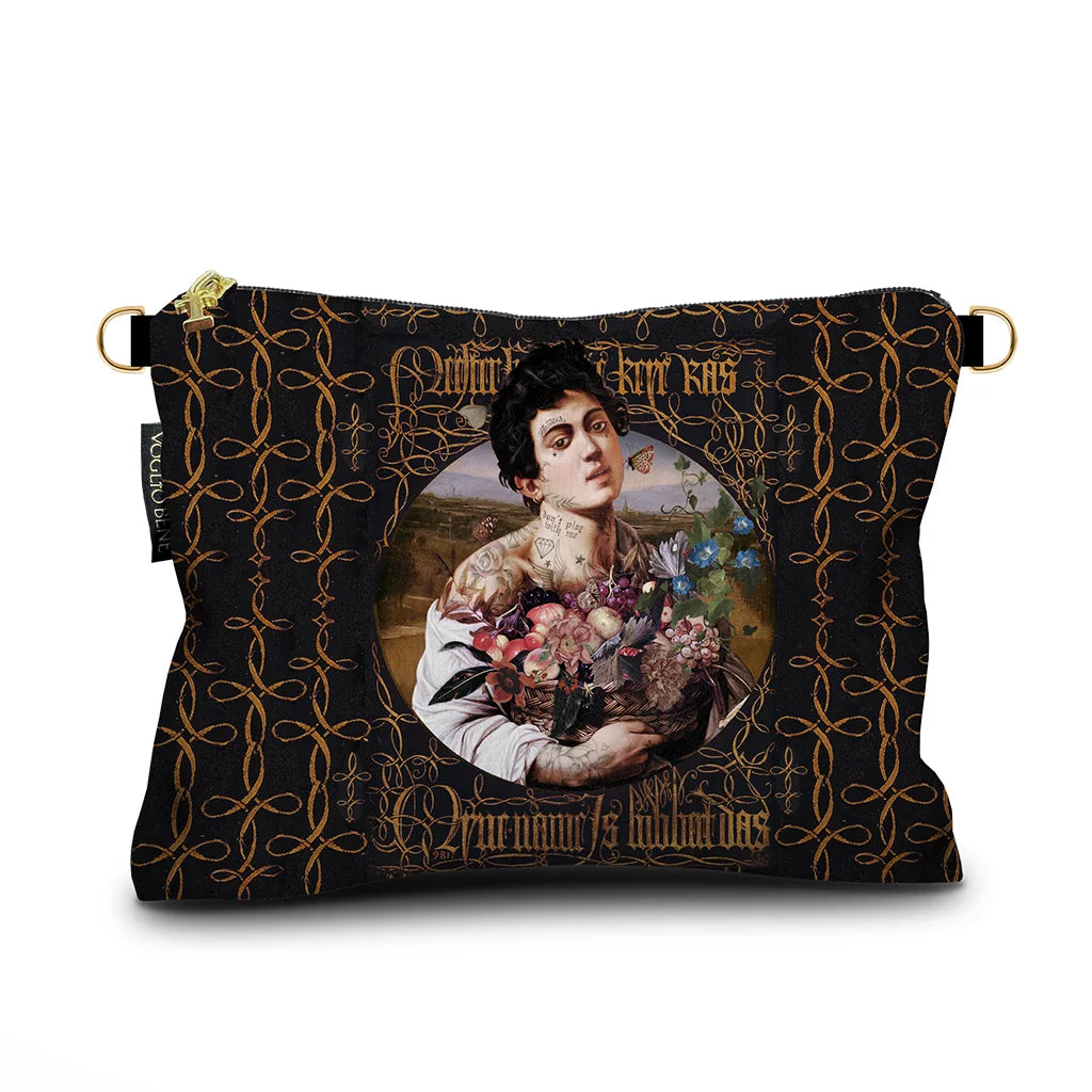 Kuvassa Voglio Bene samettilaukun etupuoli I’m Sexy -kuvituksella, jossa tatuoitu nainen pitää kukkakoria kädessään tummalla taustalla.
In the image, the front side of a Voglio Bene velvet bag with the I’m Sexy illustration, depicting a tattooed woman holding a basket of flowers against a dark background.