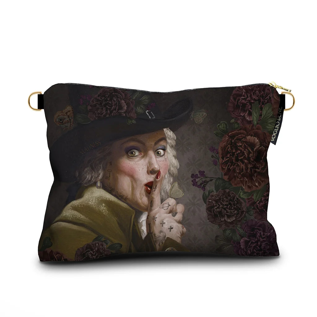 Kuvassa Voglio Bene -samettilaukun takapuoli The Key Woman -kuvituksella. Lähikuva kasvoista kukkien vieressä.
The back of the Voglio Bene velvet bag with The Key Woman illustration. Close-up of the face beside flowers.