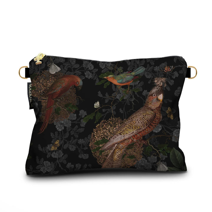 Kuvassa Voglio Bene -samettilaukku Rio -kuvituksella. Kaksi papukaijaa, eksoottinen lintu ja perhonen erottuvat mustalla metsätaustalla.
The Voglio Bene velvet bag with Rio illustration. Two parrots, an exotic bird, and a butterfly stand out against a dark forest background.