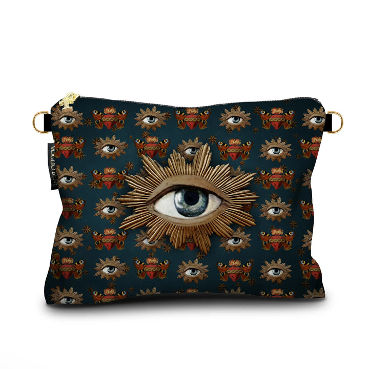 Kuvassa Voglio Bene -samettilaukun takapuoli Sacred Butterfly -kuvituksella. Iso säteilevä silmä hallitsee kuvitusta, ja sinisellä taustalla vuorottelevat sydän, jota puristavat orjantappurat ja liekit, sekä perhossiipinen sydänkuvio.
The back of the Voglio Bene velvet bag with Sacred Butterfly illustration. A large radiant eye dominates the design, while on the blue background alternate the thorn-wrapped, flaming heart and the butterfly-winged heart motif.