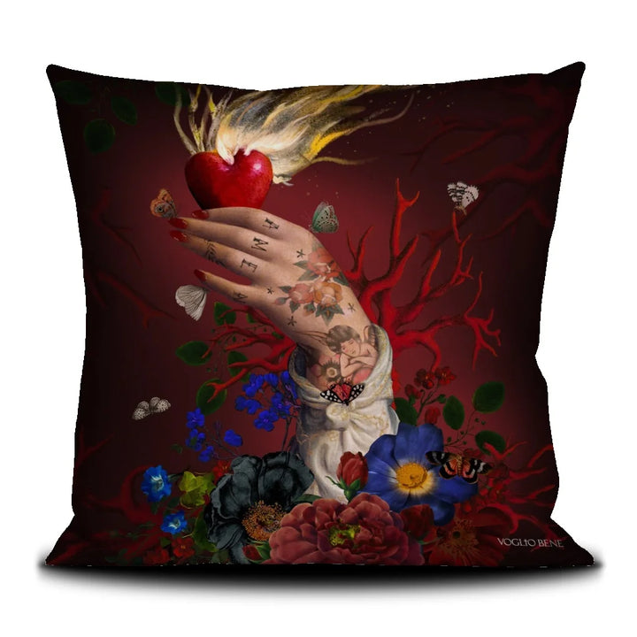 Kuvassa Voglio Bene tyyny Amen -kuvituksella. Käsi pitää palavaa sydäntä punaisella taustalla, sormissa on tatuoitu Amen ja kättä ympäröivät korallit ja perhoset.
The Voglio Bene cushion with Amen illustration. A hand holds a flaming heart against a red background, with Amen tattooed on the fingers, surrounded by corals and butterflies.