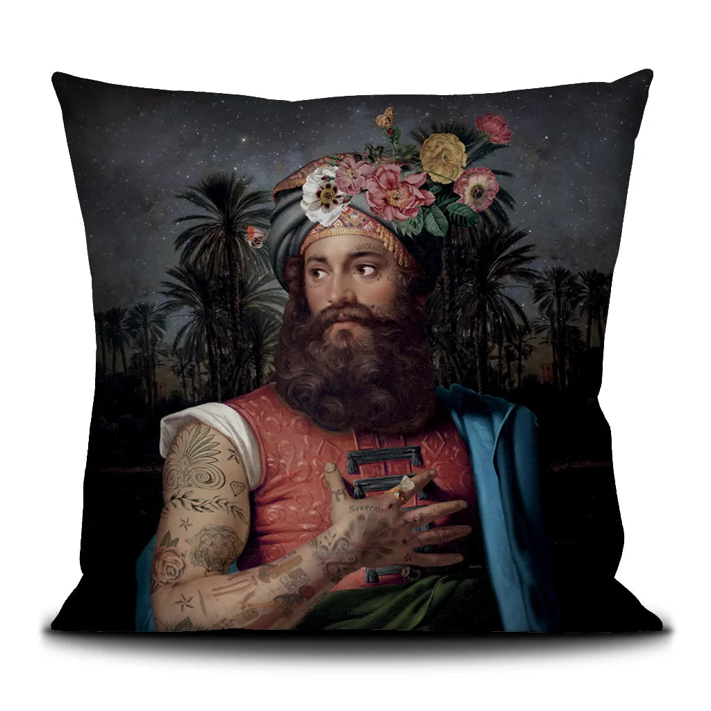 Voglio Bene The Great Belzoni -tyynyn etunäkymä, koko 50 × 50 cm, jossa tatuoitu arabialainen mies on kuvattu yömaisemassa palmujen ja tähtitaivaan reunustamana.
Front view of a Voglio Bene The Great Belzoni cushion, size 50 × 50 cm, showing a tattooed Arab man in a night scene framed by palm trees and a starry sky.