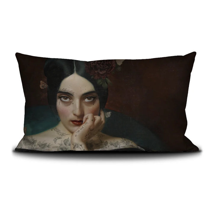 Kuvassa Voglio Bene tyynyn etupuoli Clementine -kuvituksella, jossa tatuoitu nainen tummanpunaisella taustalla katsoo intensiivisesti kohti katsojaa.
In the image, the front side of a Voglio Bene cushion with the Clementine illustration, depicting a tattooed woman on a dark red background gazing intensely at the viewer.