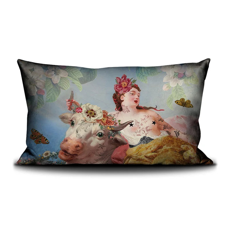 Voglio Bene Cow -tyynyn etunäkymä, jossa lehmä ja tatuoitu nainen on kuvattu yhdessä kukkaornamentein koristeltuna.
Front view of a Voglio Bene Cow cushion, showing a cow together with a tattooed woman adorned with floral ornaments.