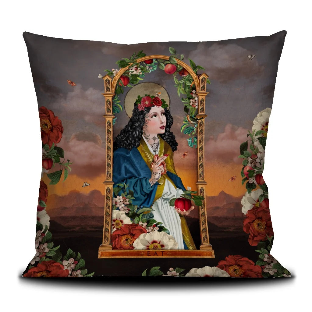 Voglio Bene Eat -tyynyn etunäkymä. Kuvassa tummahiuksinen, tatuoitu nainen tekee merkin kädellään ja katsoo ylös taivaaseen kultaisissa kehyksissä.
Front view of a Voglio Bene Eat cushion. The illustration shows a dark-haired, tattooed woman making a hand gesture while looking up toward the sky inside a golden frame.