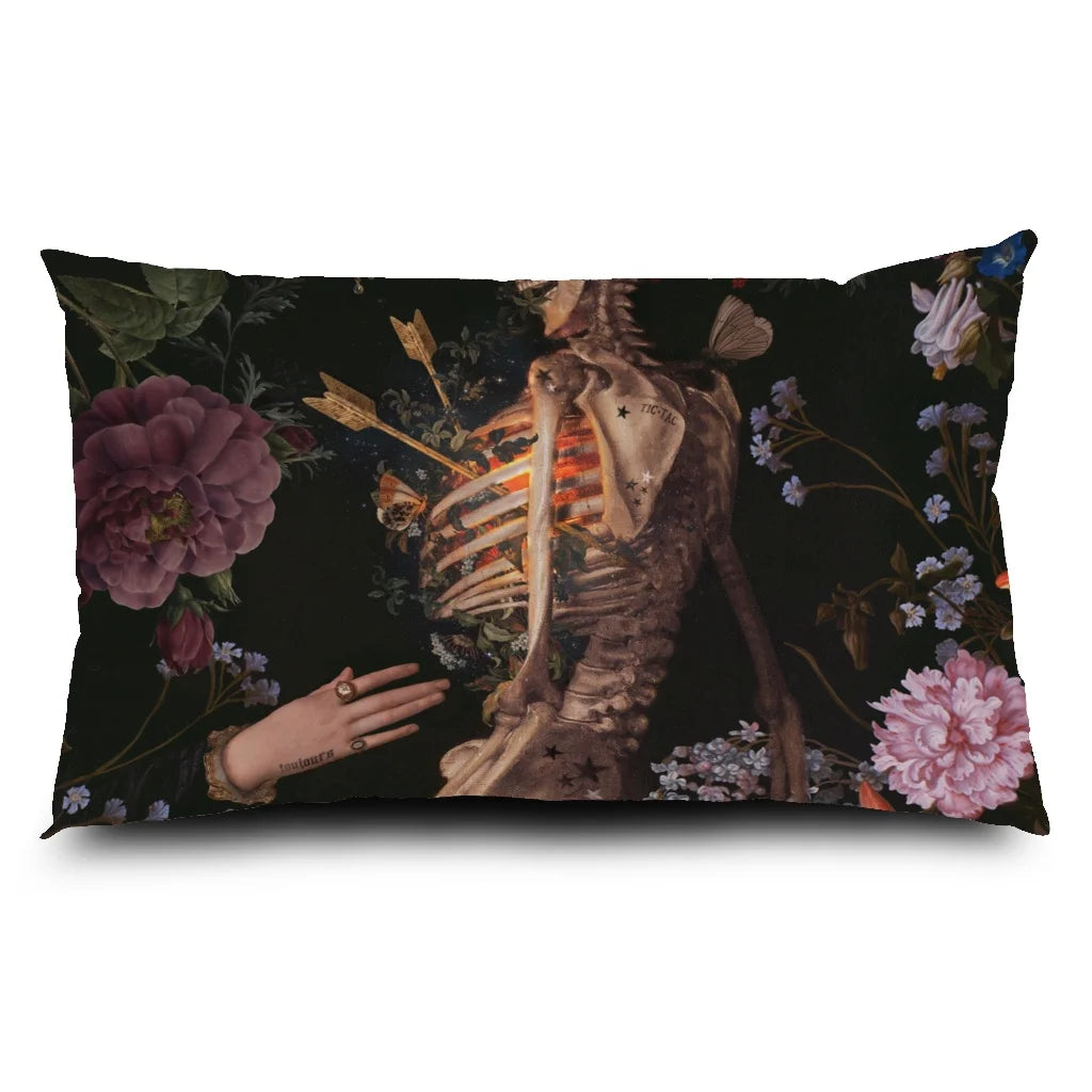 Voglio Bene -tyynyn etupuoli The Life -kuvituksella. Luurankoa ympäröivät kädet, ja kokonaisuutta ympäröivät kasvit ja perhoset.
Front side of the Voglio Bene cushion featuring The Life illustration. The  skeleton is surrounded by hands, with plants and butterflies around them.