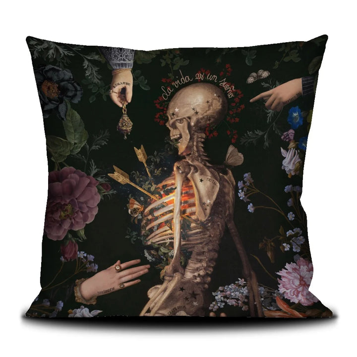 Voglio Bene -tyynyn etupuoli The Life -kuvituksella. Luurankoa ympäröivät kädet, ja kokonaisuutta ympäröivät kasvit ja perhoset.
Front side of the Voglio Bene cushion featuring The Life illustration. The  skeleton is surrounded by hands, with plants and butterflies around them.