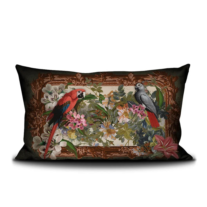 Voglio Bene Parrot -tyynyn etunäkymä. Kuvassa kaksi papukaijaa istuu kukkaornamentti-asetelmassa rehevän taustan edessä.
Front view of a Voglio Bene Parrot cushion. The illustration shows two parrots perched within a floral ornamental arrangement against a lush backdrop.
