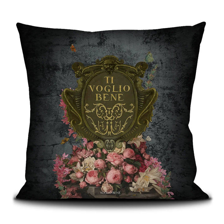 Voglio Bene Poderosa-tyynyn takanäkymä. Kuvassa vaalenpunaisia ja vaaleita kukkia kultaisen vaakunan alla.
Back view of the Voglio Bene Poderosa cushion. The image features light pink and pale flowers beneath a golden emblem.